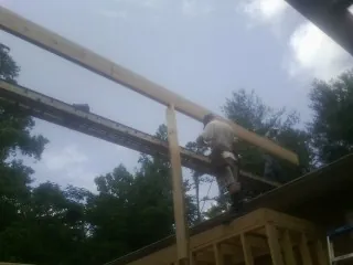 Carpenter setting a ridge beam over a new addition frame — Ice Dam Removal by Roofing Brothers in Luebbering