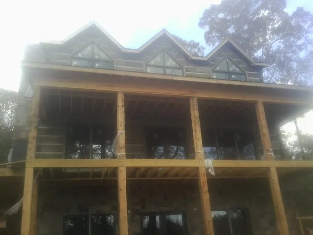 Dormers and porch framing on a large log home under construction — Roof Coating work by our crew in Luebbering