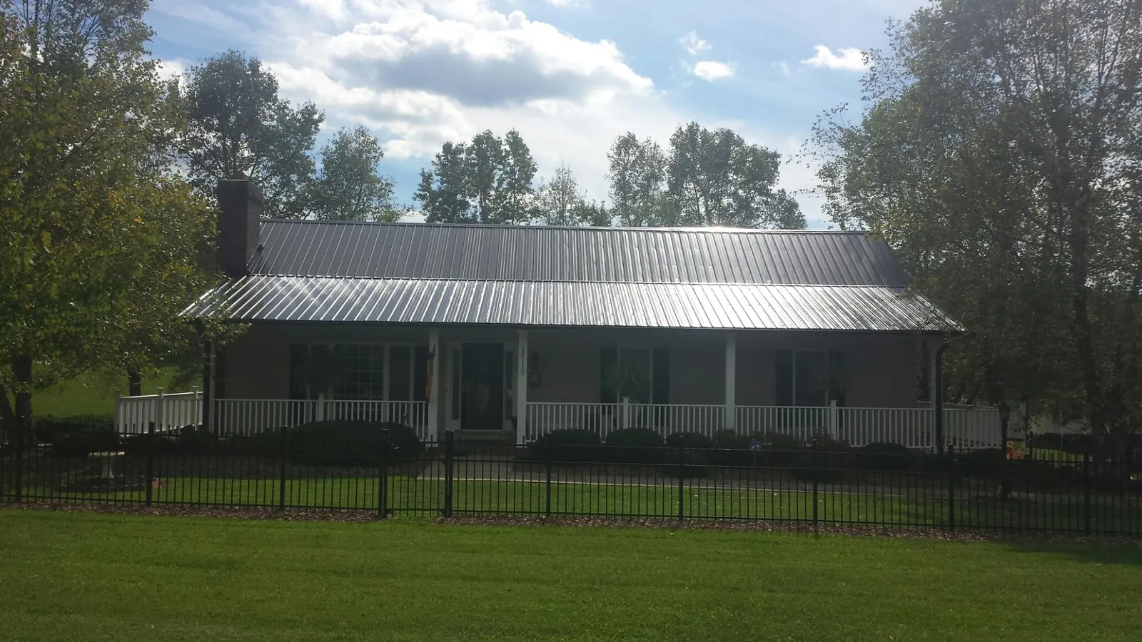 Gray metal roof on a brick ranch with a full width front porch — Gutter Guard Installation work by our crew in Luebbering