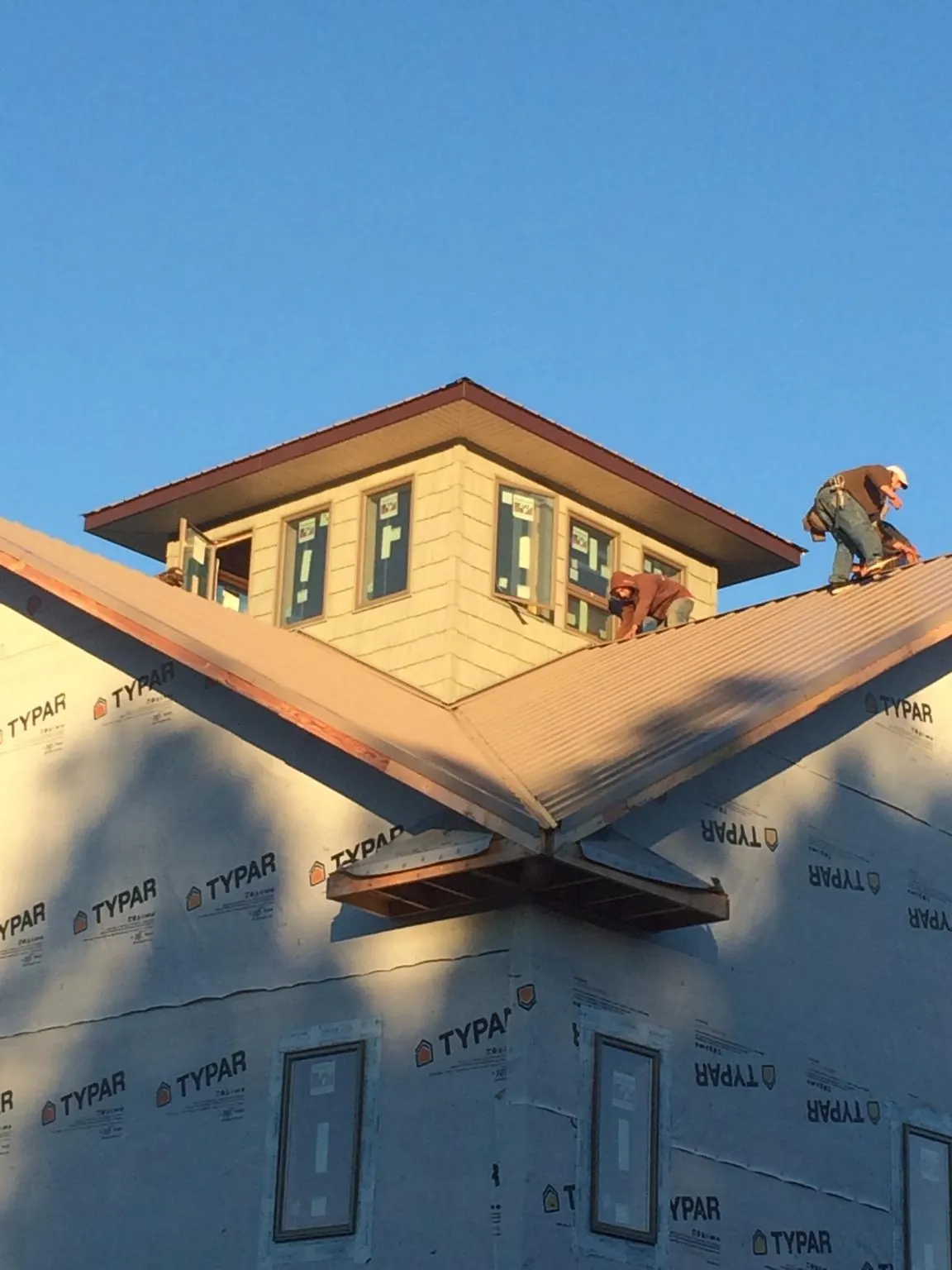 Roofers working around a rooftop cupola on a new metal roof at sunset — Roof Waterproofing in Luebbering by Roofing Brothers